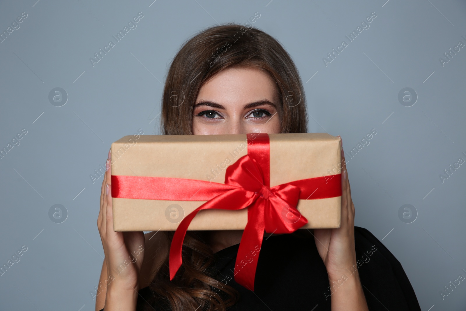 Photo of Happy woman with gift box on grey background. Christmas party