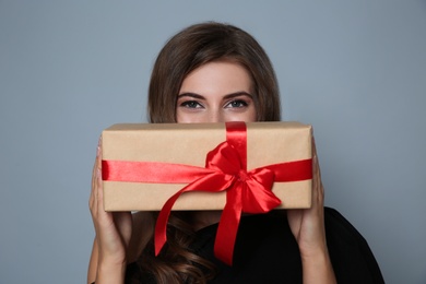 Happy woman with gift box on grey background. Christmas party