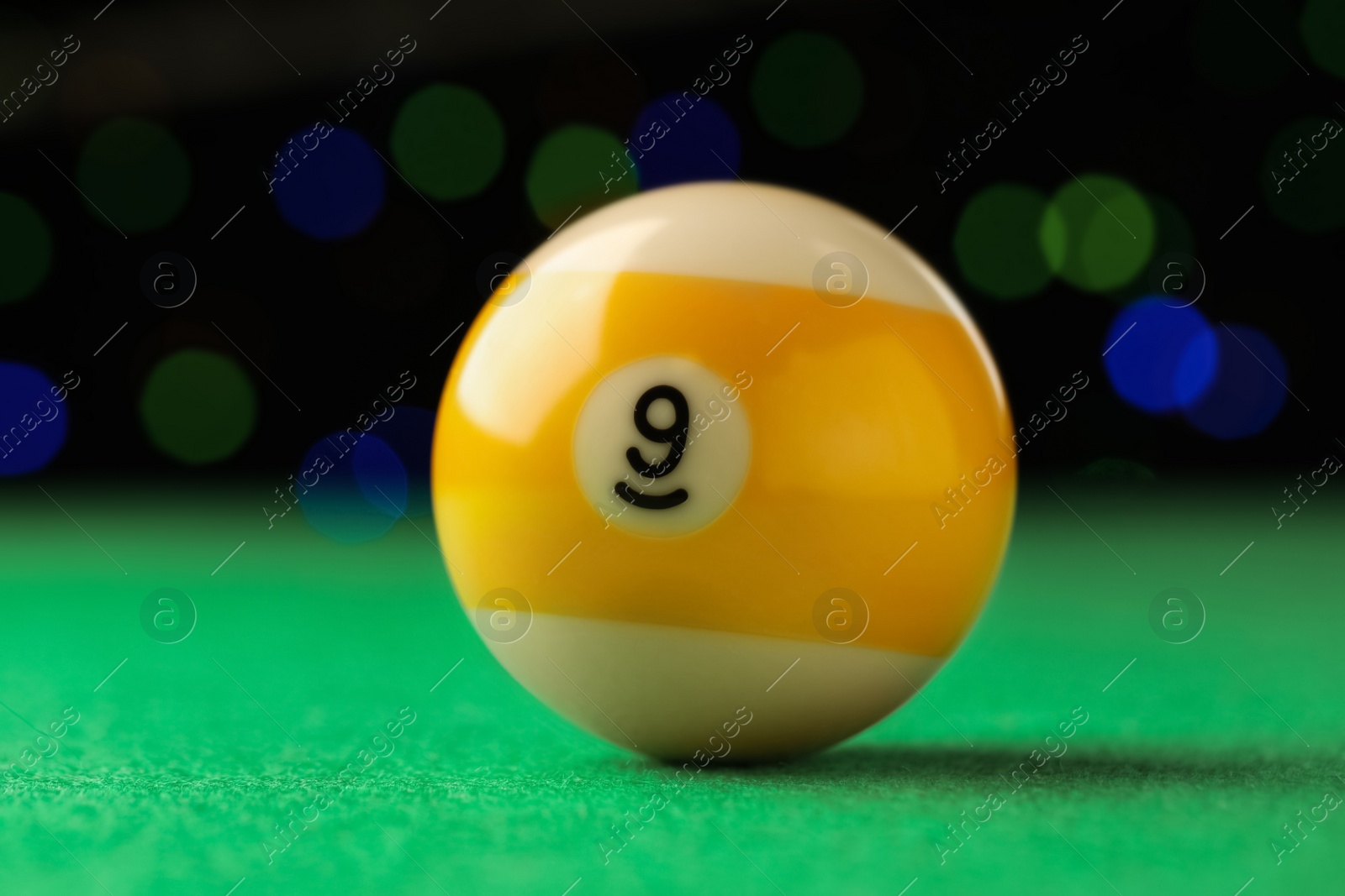Photo of Billiard ball with number 9 on green table, closeup
