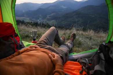 Photo of Man resting inside of camping tent in mountains, closeup