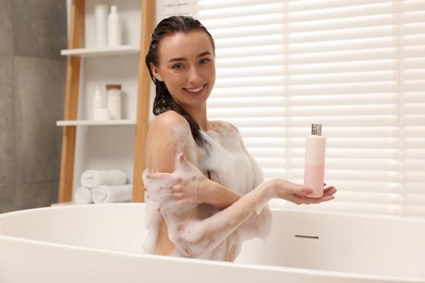 Photo of Woman taking bath with shower gel in bathroom