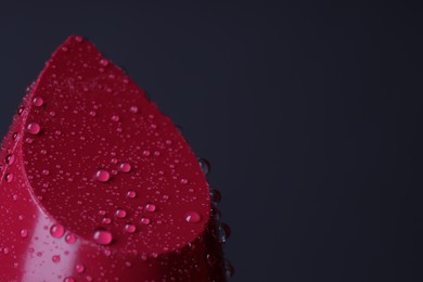 Red lipstick with water drops on dark gray background, macro view. Space for text