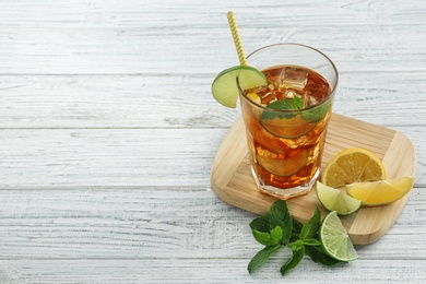 Photo of Glass of delicious iced tea  on white wooden table. Space for text