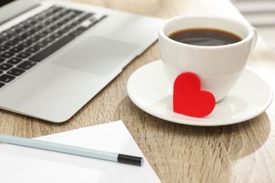 Photo of Cup with red heart and laptop on table. Valentine's day celebration