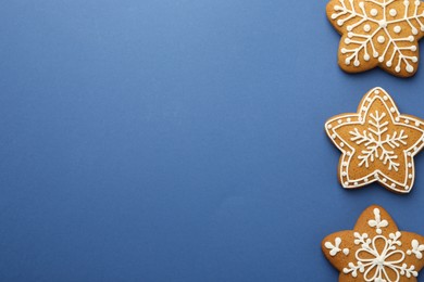 Photo of Tasty star shaped Christmas cookies with icing on blue background, flat lay. Space for text