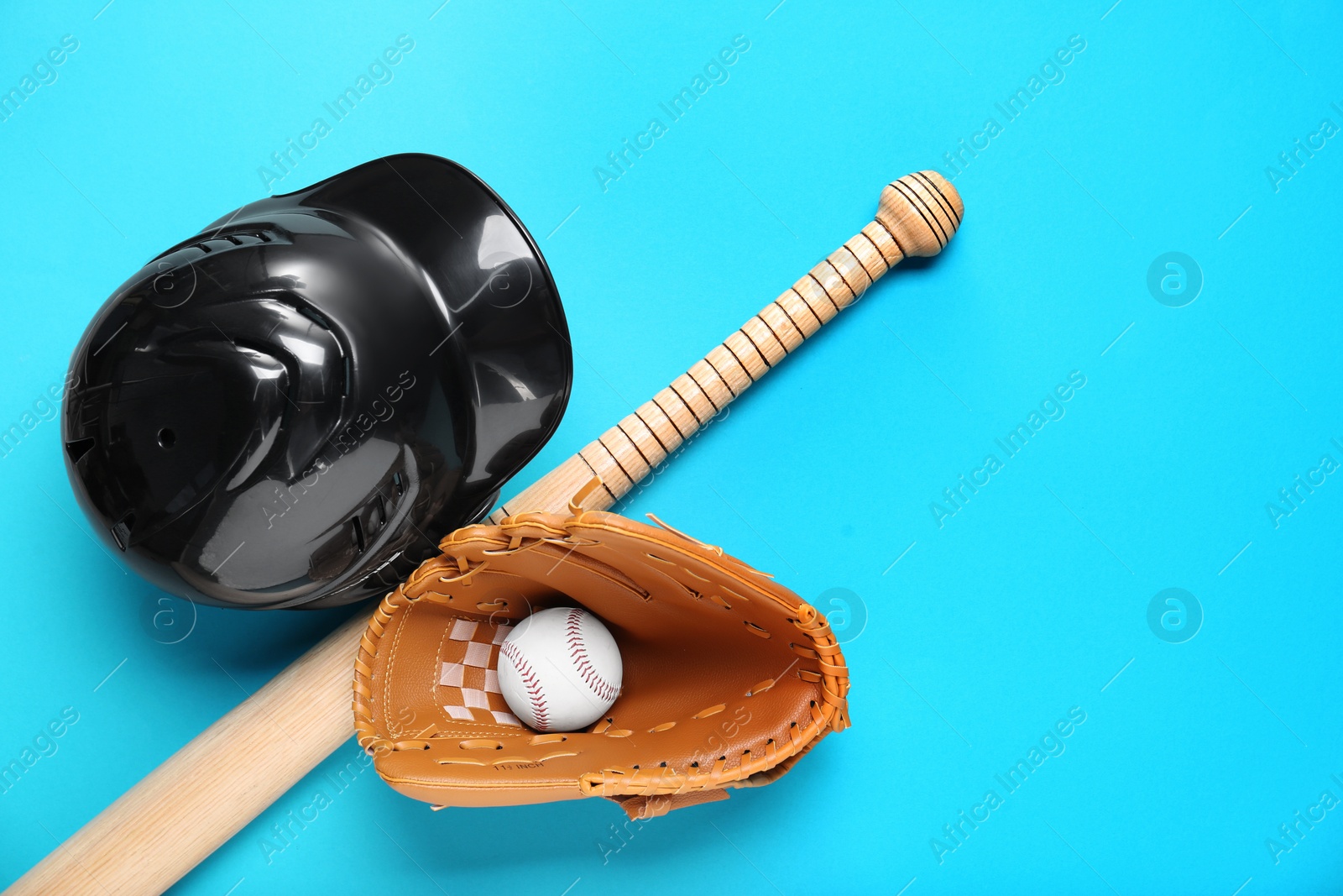 Photo of Baseball glove, bat, ball and batting helmet on light blue background, flat lay