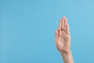 Photo of Woman giving high five on light blue background, closeup. Space for text