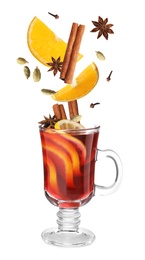 Cut orange and different spices falling into glass cup of mulled wine on white background 