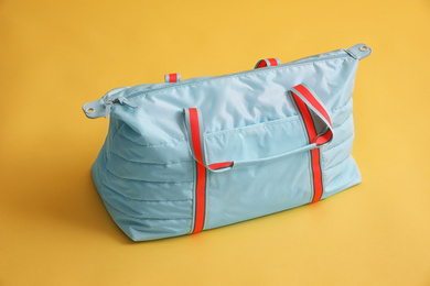 Photo of Stylish gym bag on yellow background. Sports equipment