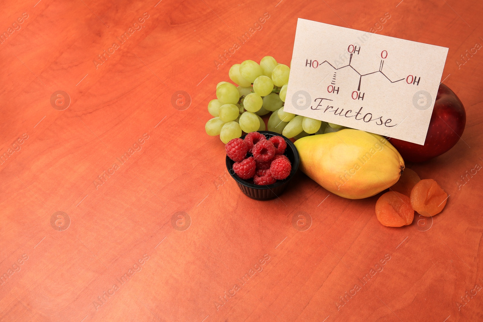 Photo of Card with word Fructose, delicious ripe fruits, raspberries and dried apricots on wooden table, space for text