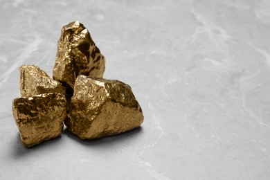 Photo of Gold nuggets on light grey marble table, closeup. Space for text