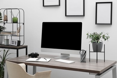 Photo of Cozy workspace with computer on desk near white wall at home