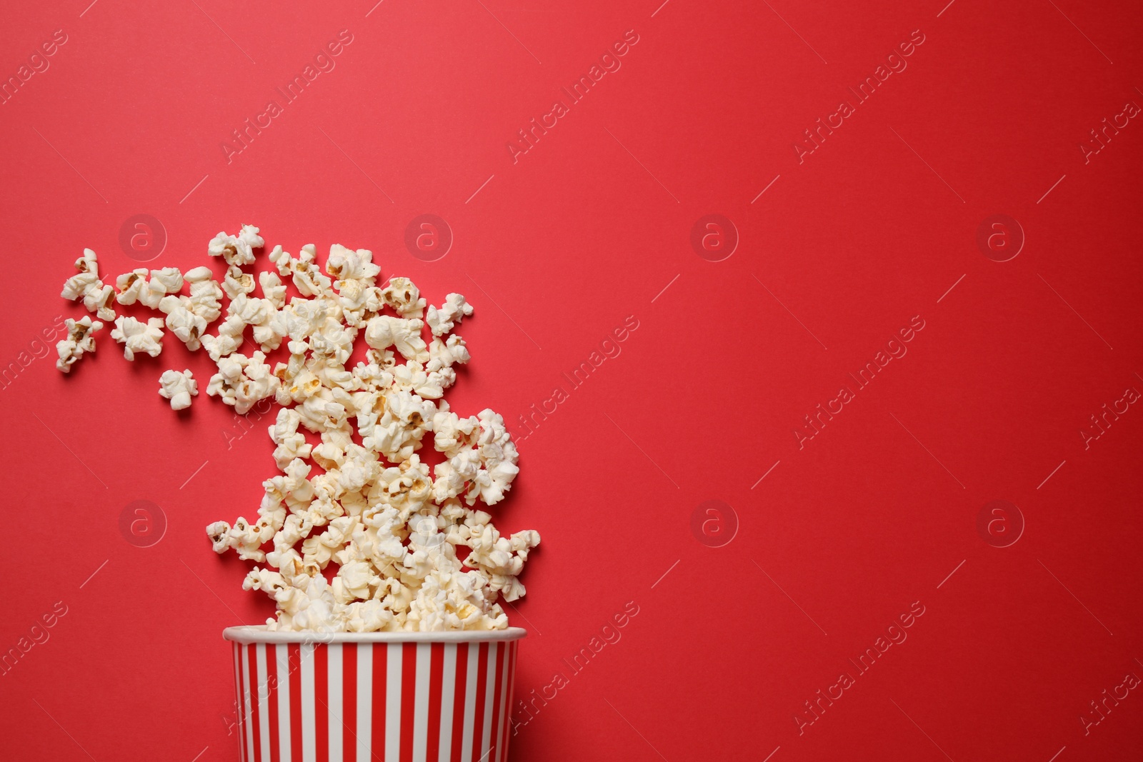 Photo of Delicious popcorn on red background, top view. Space for text