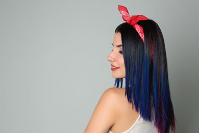 Young woman with bright dyed hair on light background