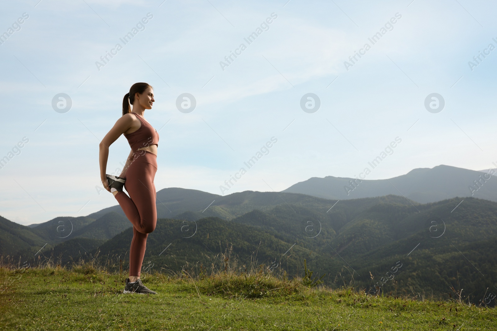 Photo of Young woman doing morning exercise in mountains, space for text