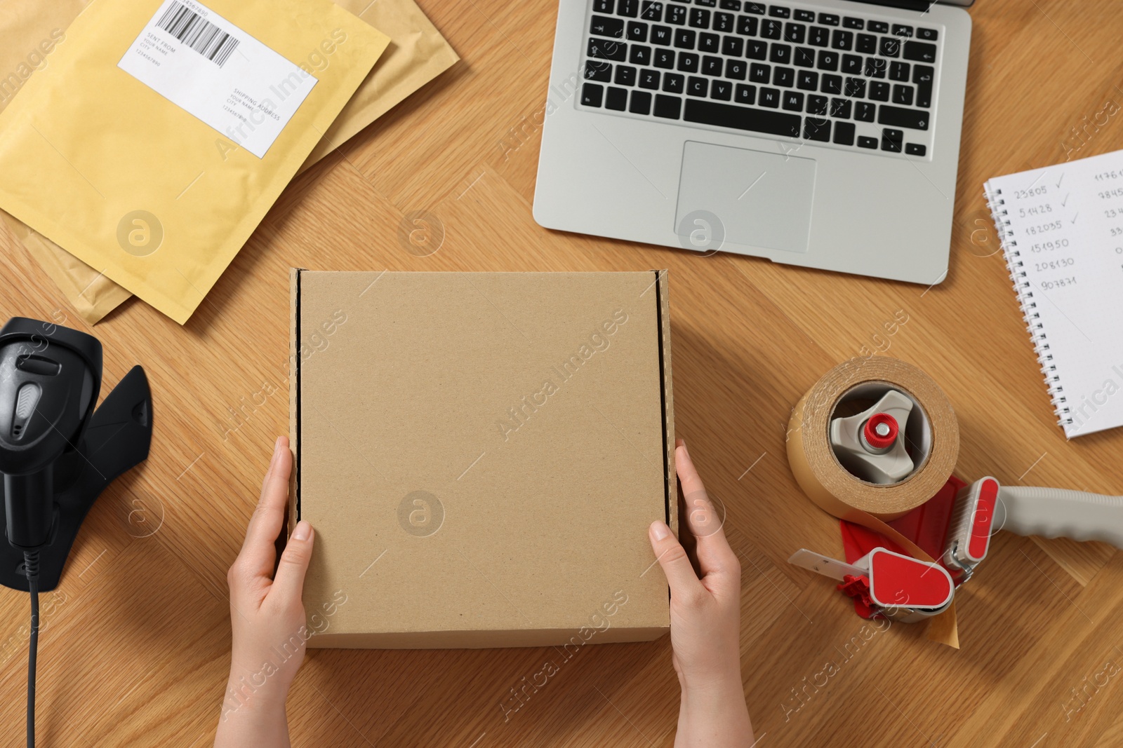 Photo of Woman with parcel at wooden table, top view. Online store