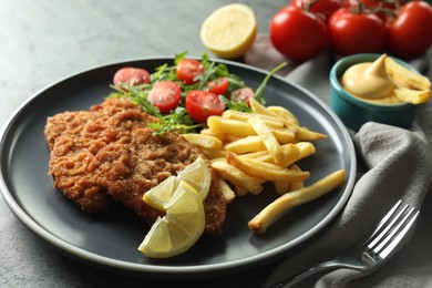 Photo of Tasty schnitzels served with potato fries, tomatoes and arugula on grey table, closeup