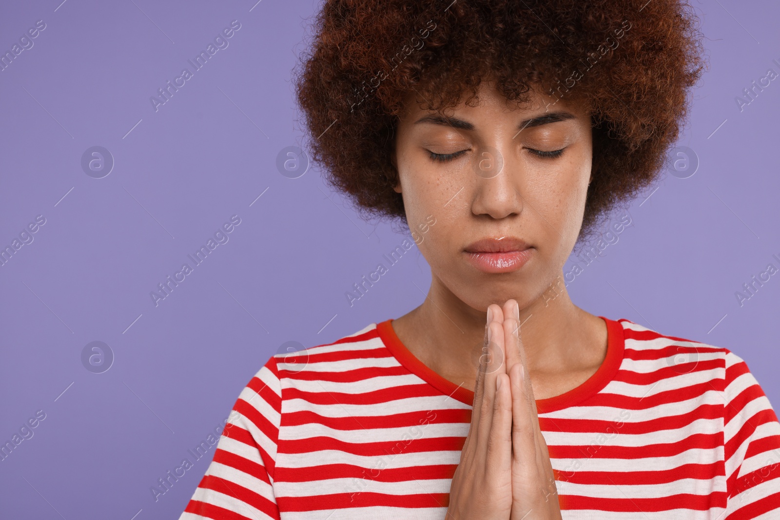 Photo of Woman with clasped hands praying to God on purple background. Space for text