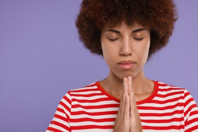 Photo of Woman with clasped hands praying to God on purple background. Space for text