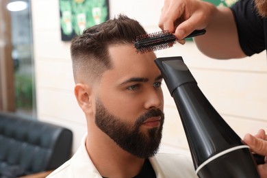 Photo of Professional hairdresser working with client in barbershop, closeup