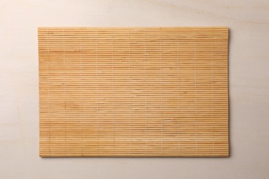 Bamboo mat on beige table, top view. Space for text