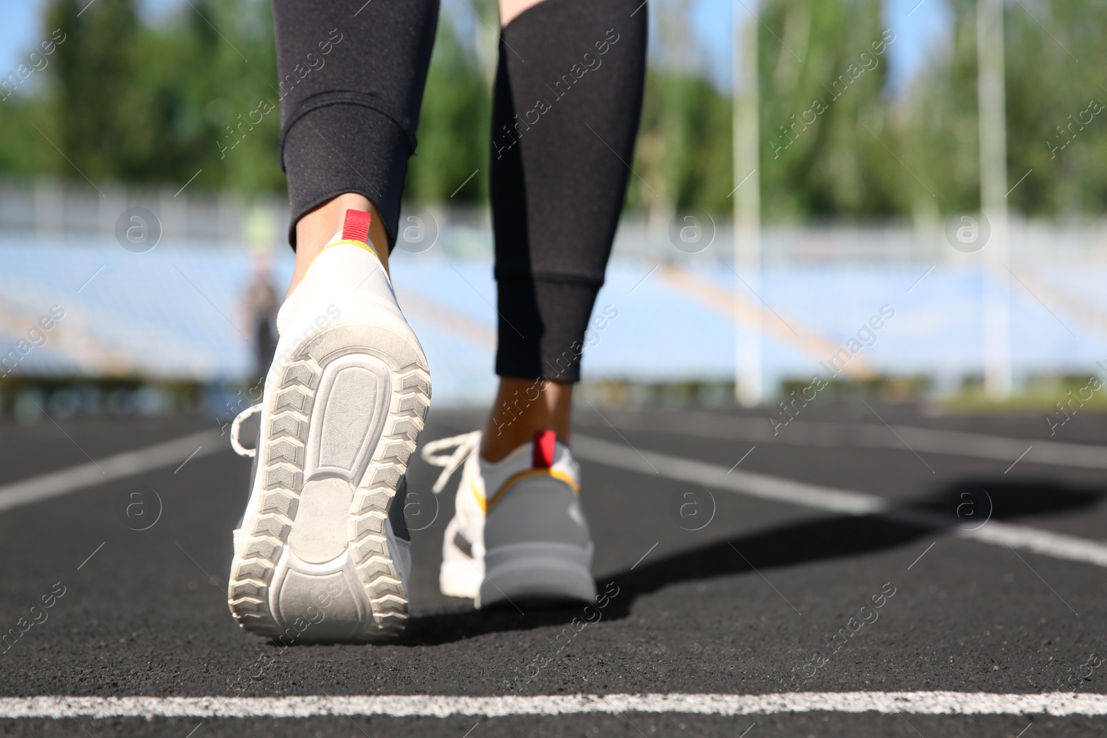 Photo of Sporty woman running at stadium on sunny morning, focus on legs