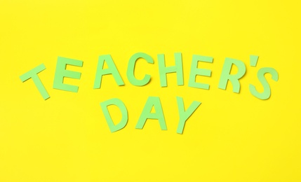 Words TEACHER'S DAY on yellow background, flat lay