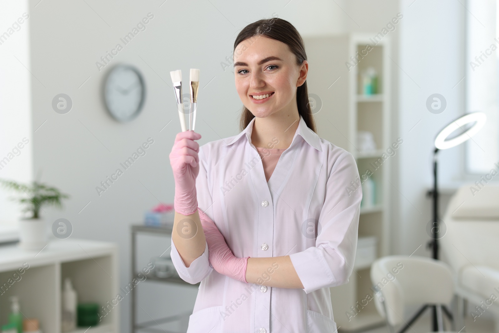 Photo of Cosmetologist with cosmetic brushes in modern clinic