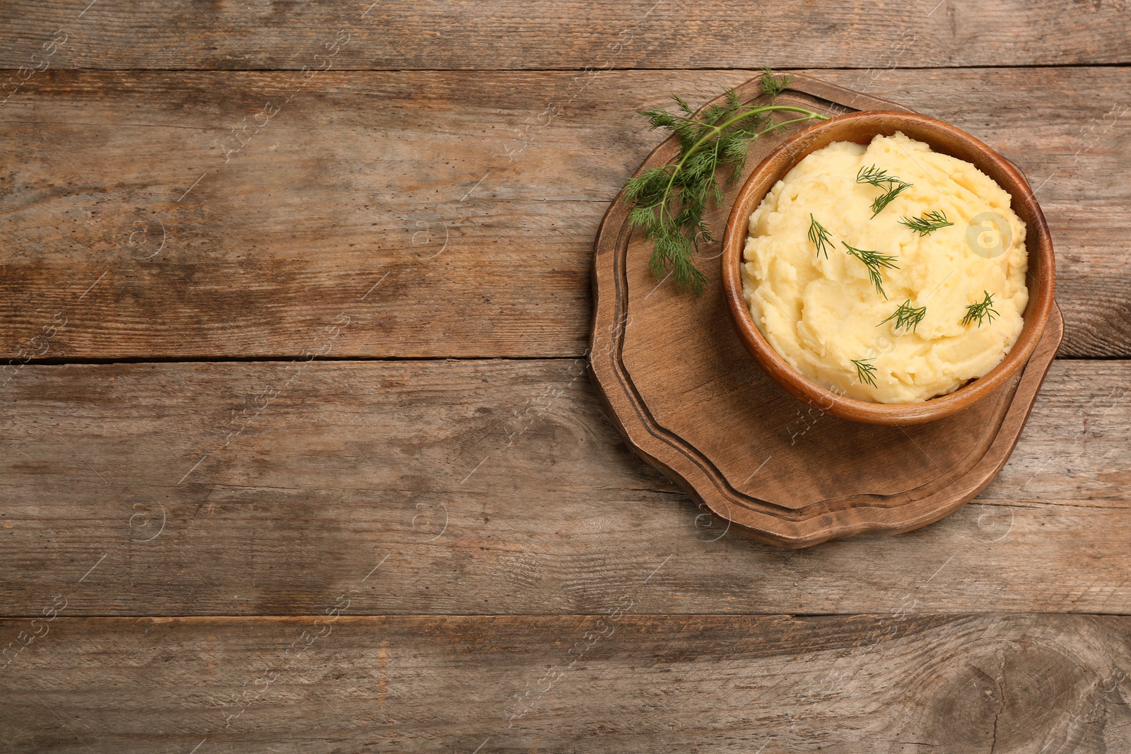 Photo of Bowl with mashed potatoes on wooden background, top view. Space for text