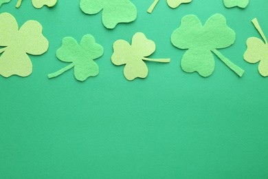 Photo of St. Patrick's day. Decorative clover leaves on green background, flat lay. Space for text