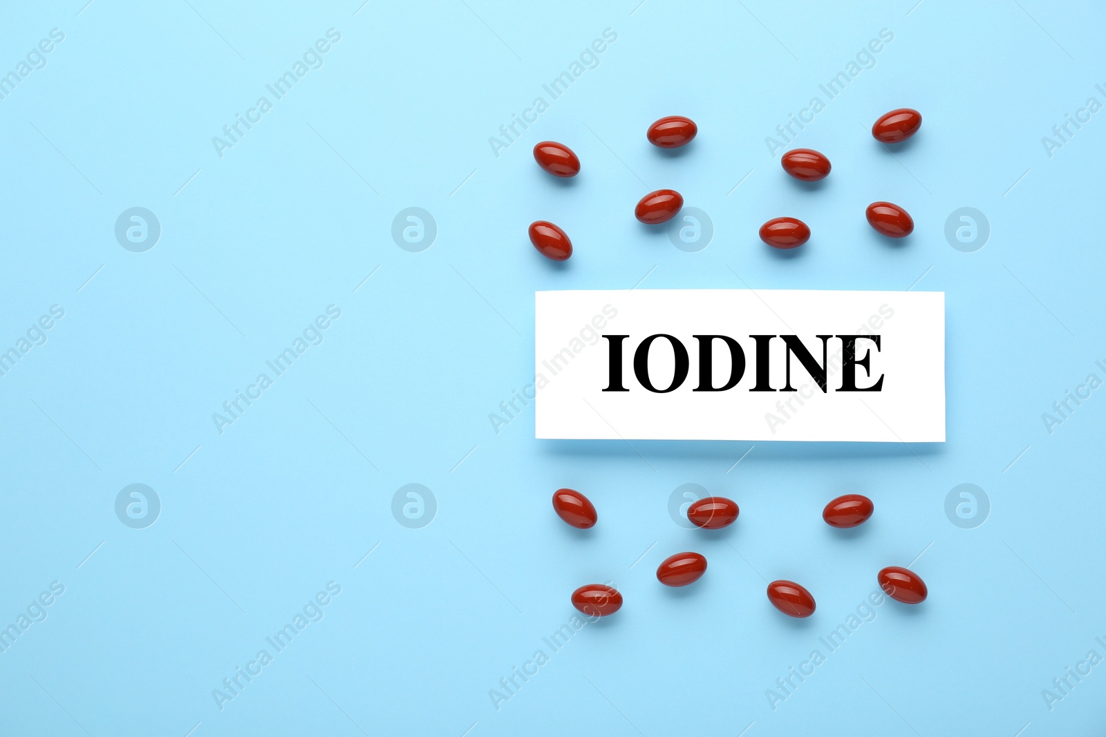 Photo of Card with word Iodine and pills on light blue background, flat lay. Space for text