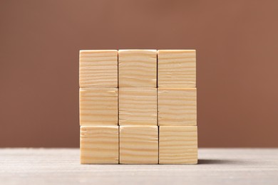 Blank cubes on wooden table against brown background