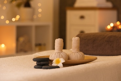 Photo of Herbal compresses and stones on massage table in spa salon