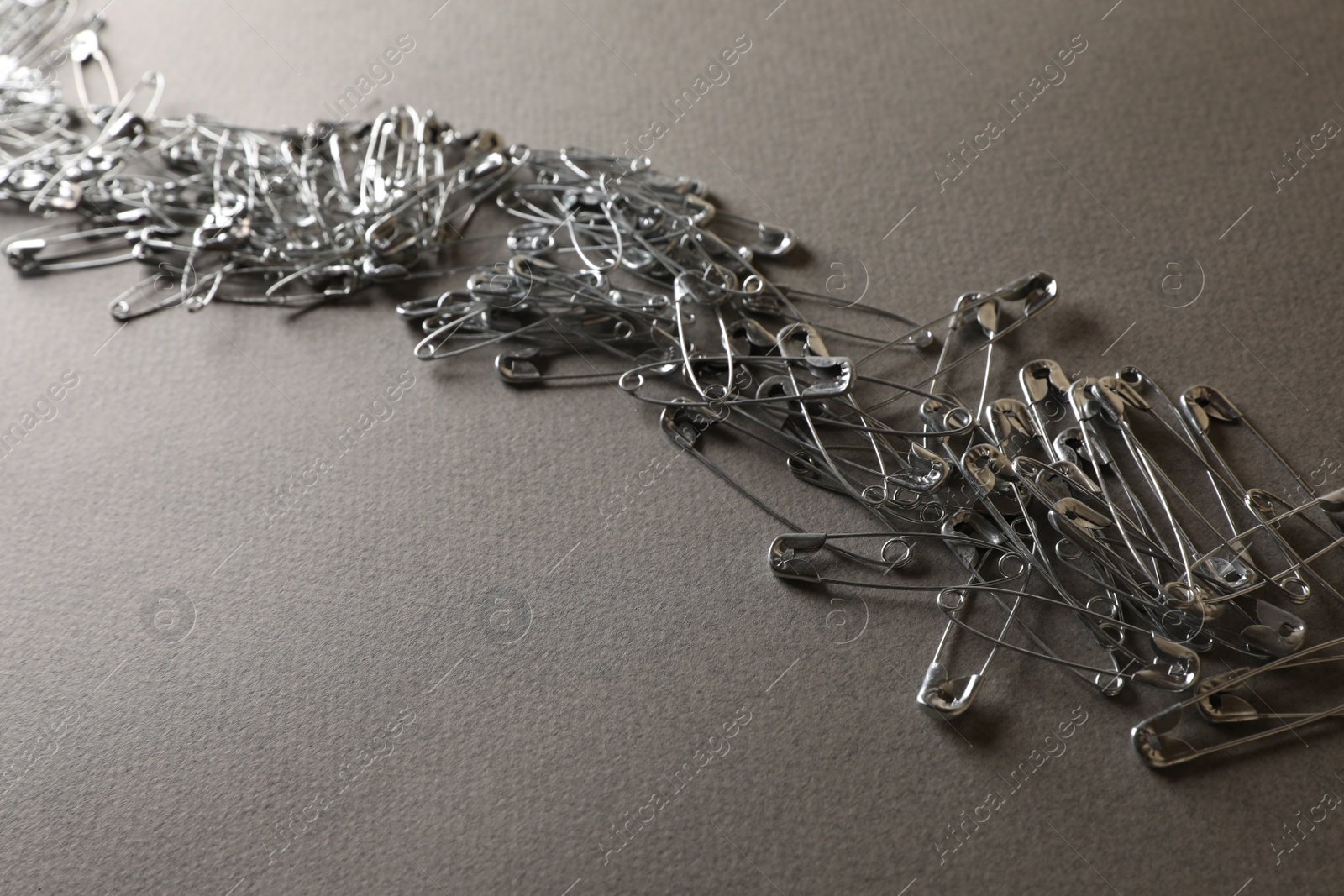 Photo of Many safety pins on light grey textured background