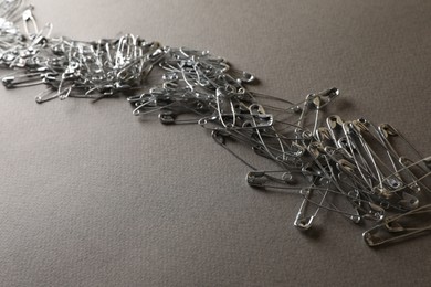 Many safety pins on light grey textured background