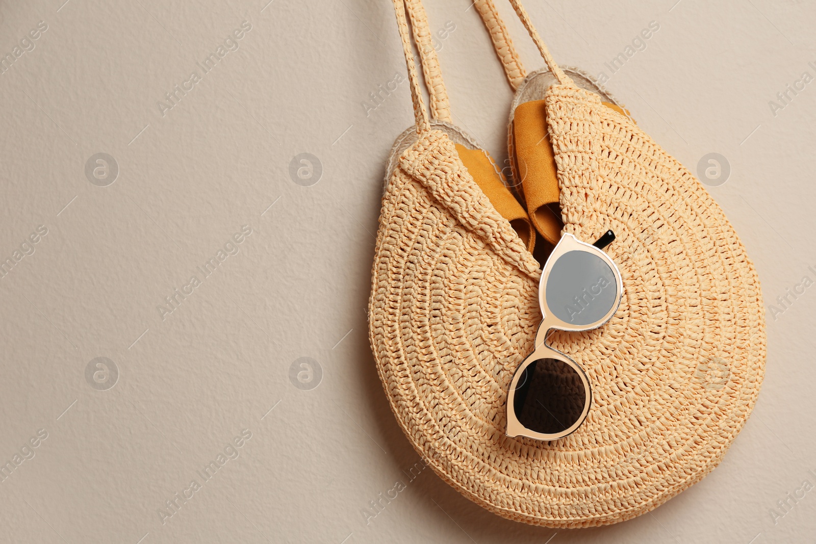 Photo of Elegant woman's straw bag with shoes and sunglasses  on beige background, top view. Space for text