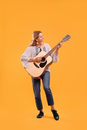 Happy hippie woman playing guitar on yellow background