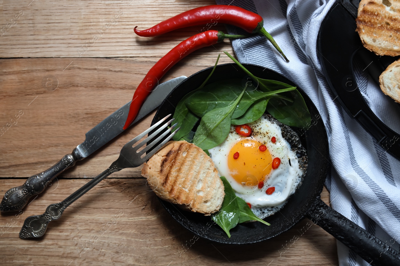 Photo of Delicious fried egg with spinach and chilli served on wooden table, flat lay