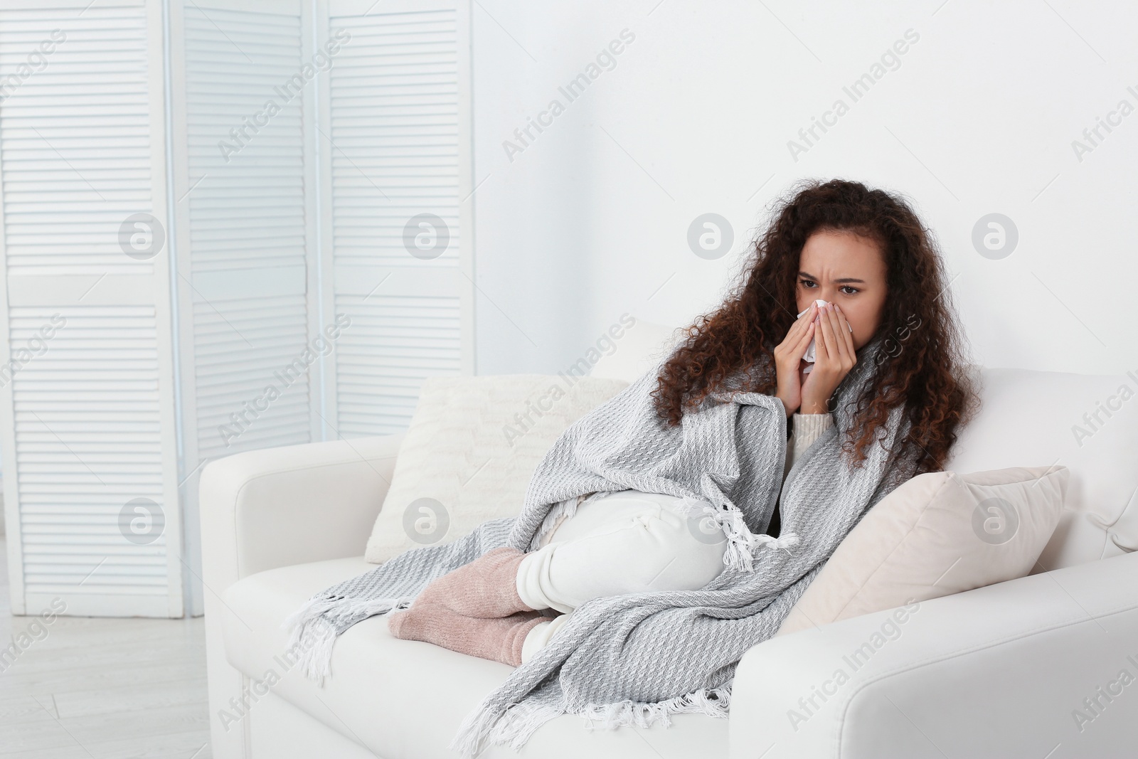 Photo of Sick African American woman with tissue at home, space for text