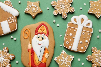 Photo of Tasty gingerbread cookies on green background, flat lay. St. Nicholas Day celebration