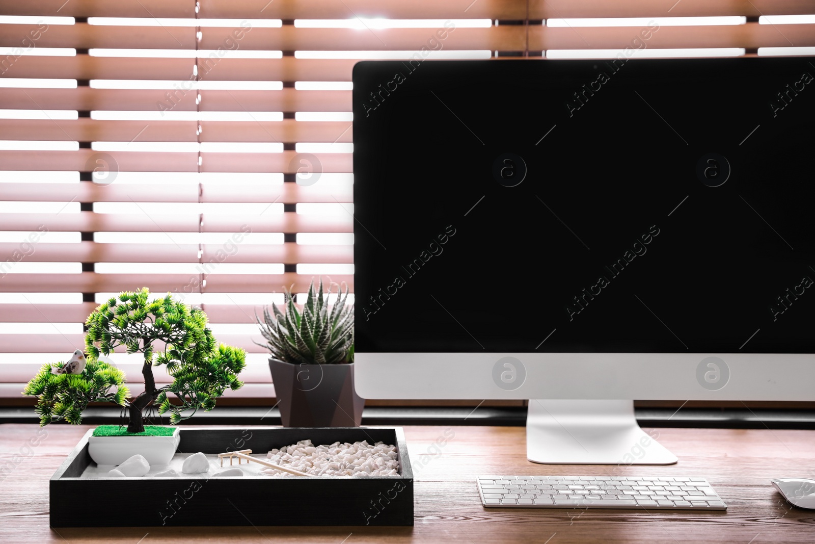 Photo of Modern workplace with beautiful miniature zen garden and computer in room