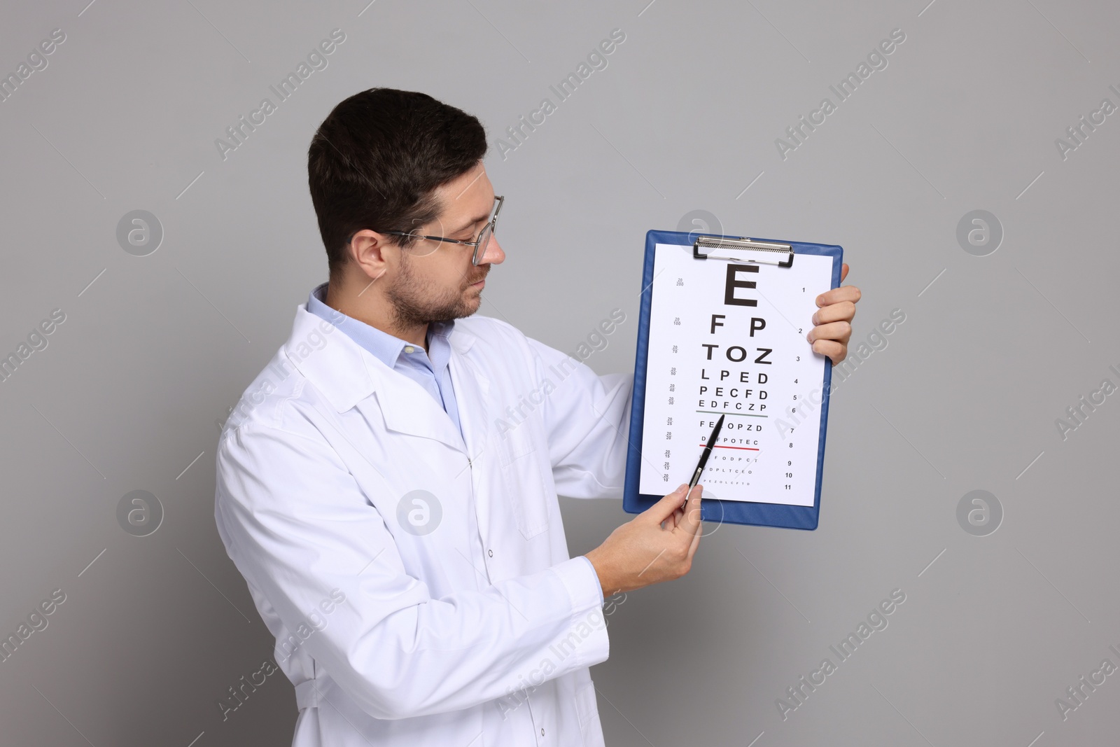 Photo of Ophthalmologist pointing at vision test chart on gray background