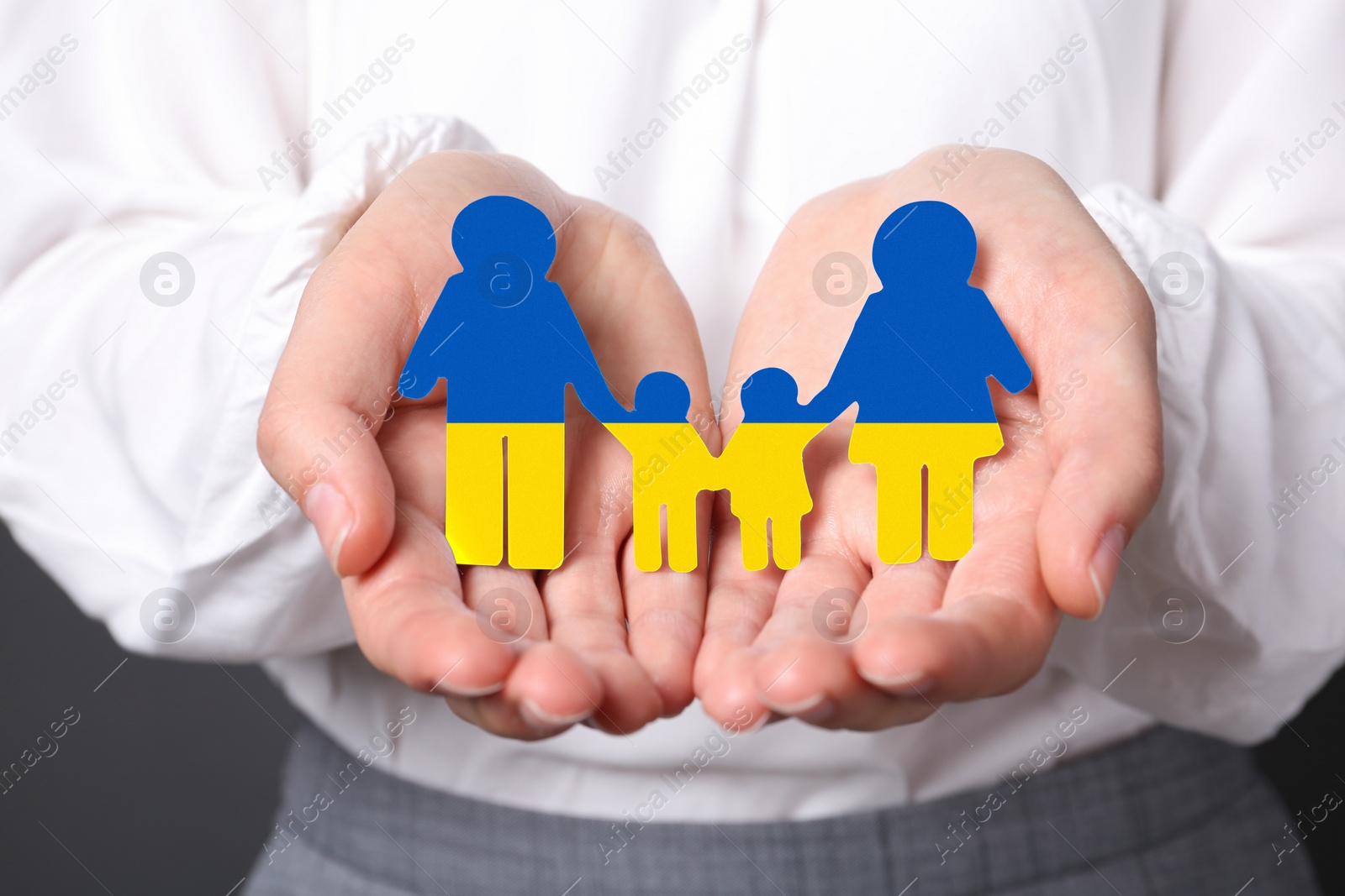 Image of Woman holding cutout paper family in colors of Ukrainian flag, closeup