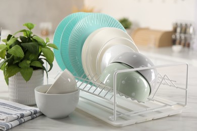 Many different clean dishware and houseplant on white marble table in kitchen