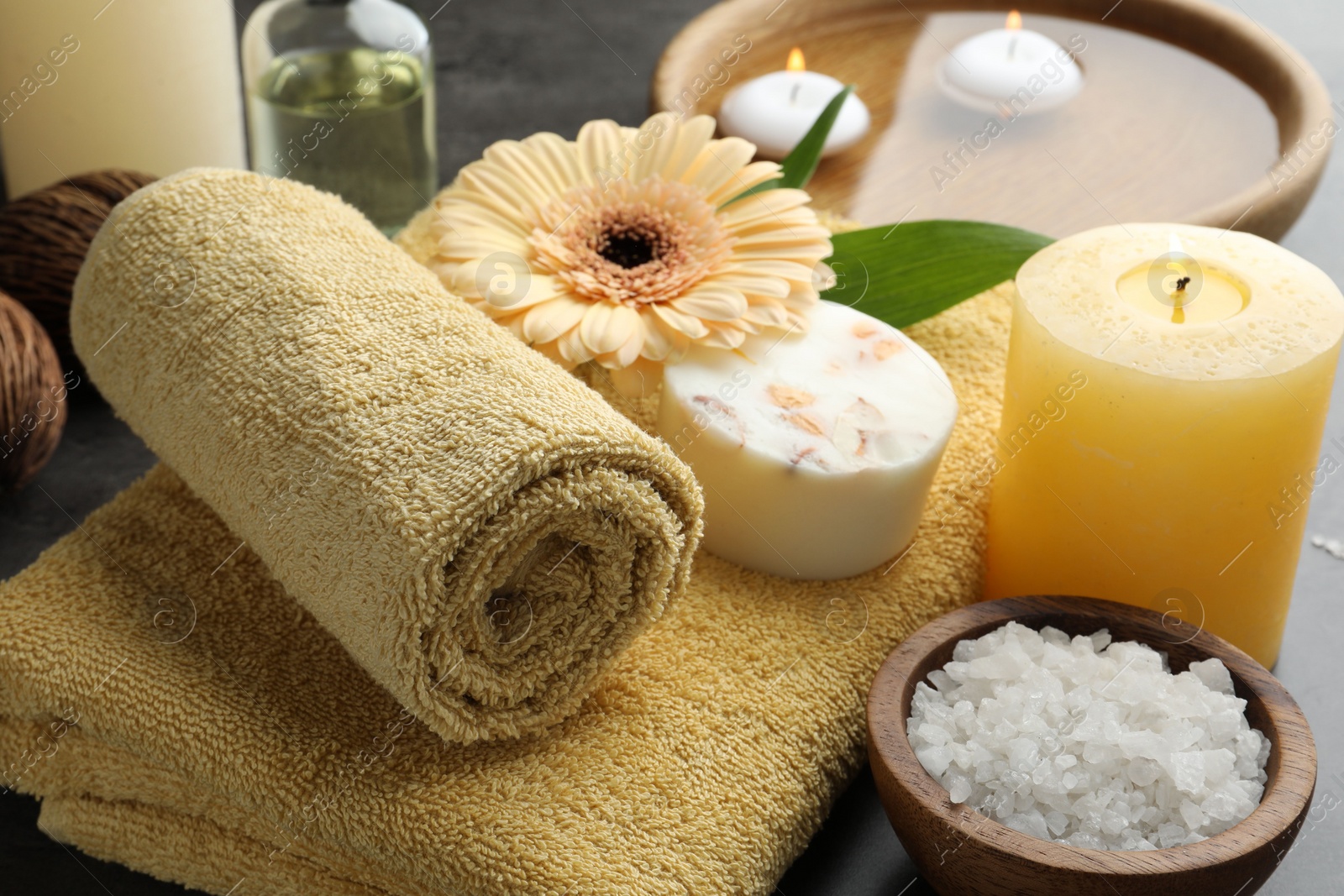 Photo of Composition with different spa products and burning candle on table, closeup