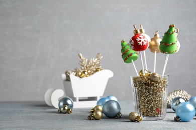 Delicious Christmas themed cake pops and festive decor on wooden table against grey background. Space for text