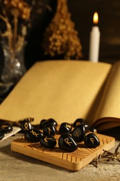 Composition with black rune stones and old book on wooden table