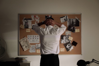 Detective looking at evidence board in office