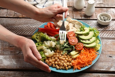 Photo of Balanced diet and healthy foods. Woman eating dinner at wooden table, closeup