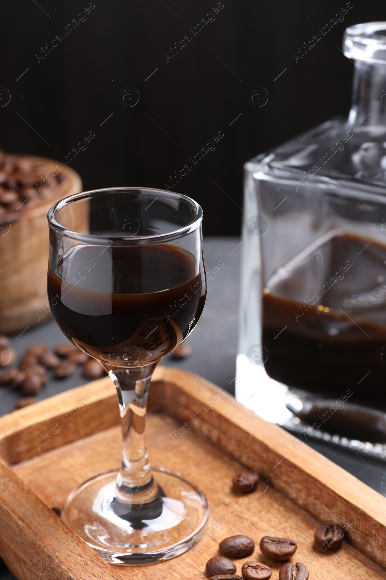 Photo of Coffee liqueur and beans on grey table, closeup